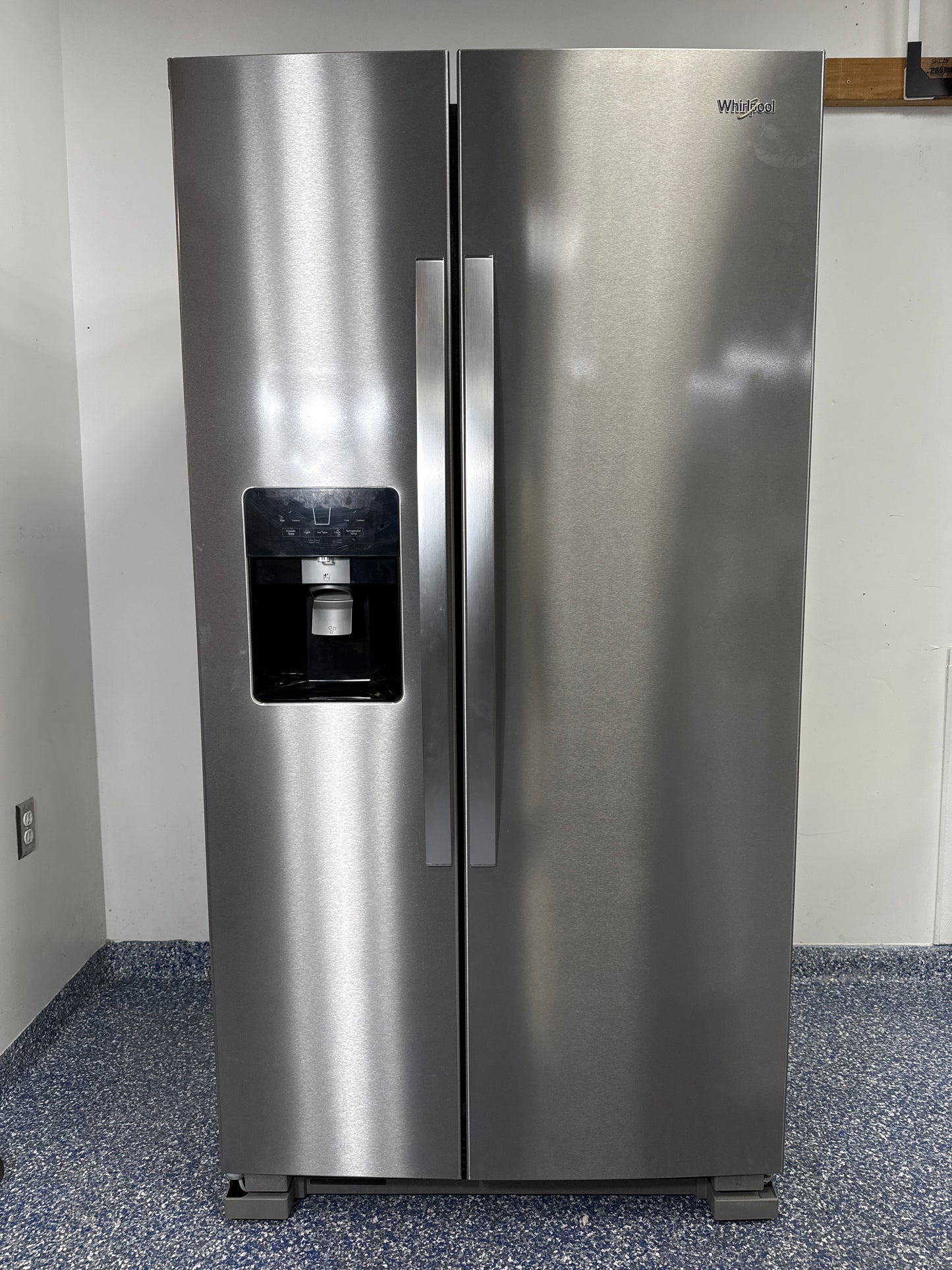 A full view of the Whirlpool WRS325SDHZ side-by-side refrigerator in fingerprint-resistant stainless steel with an exterior water and ice dispenser. Find this great deal at Appliance Shark in Overland Park.