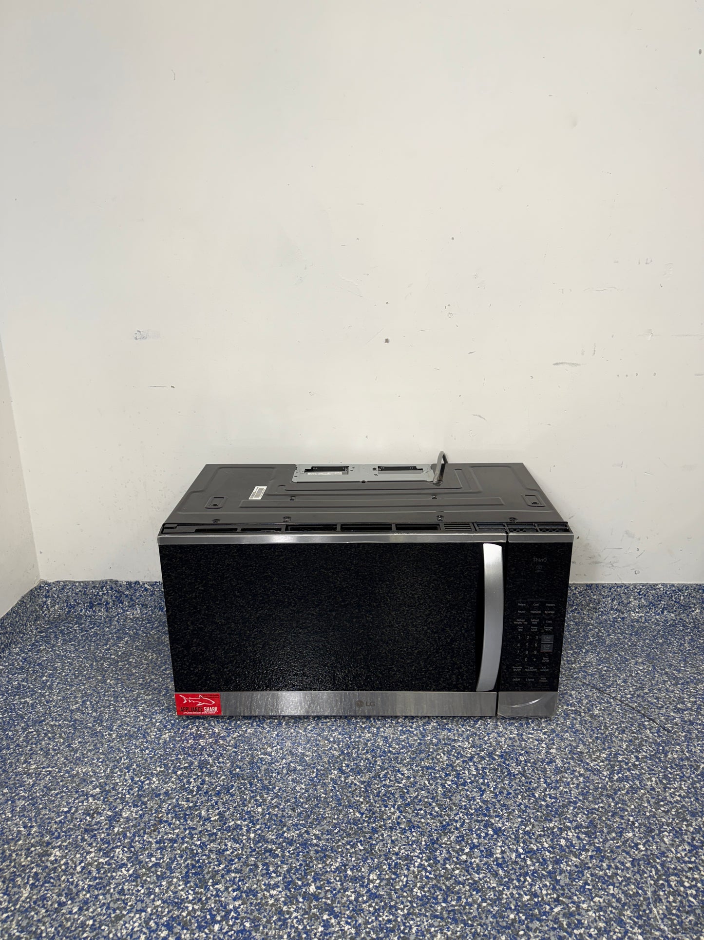 A full frontal image of the LG MVEM1825F over-the-range microwave, highlighting its PrintProof™ Stainless Steel finish, recessed pocket handle, and sleek modern design. On sale at Appliance Shark – Scratch & Dent store | Kansas City.