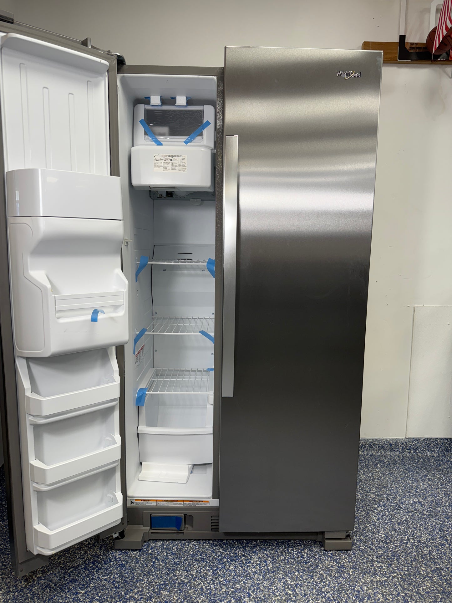 View of the interior of the Whirlpool WRS315SDHZ freezer, highlighting the indoor ice maker and wire shelving. On sale at Appliance Shark - Scratch & Dent store | Kansas City.
