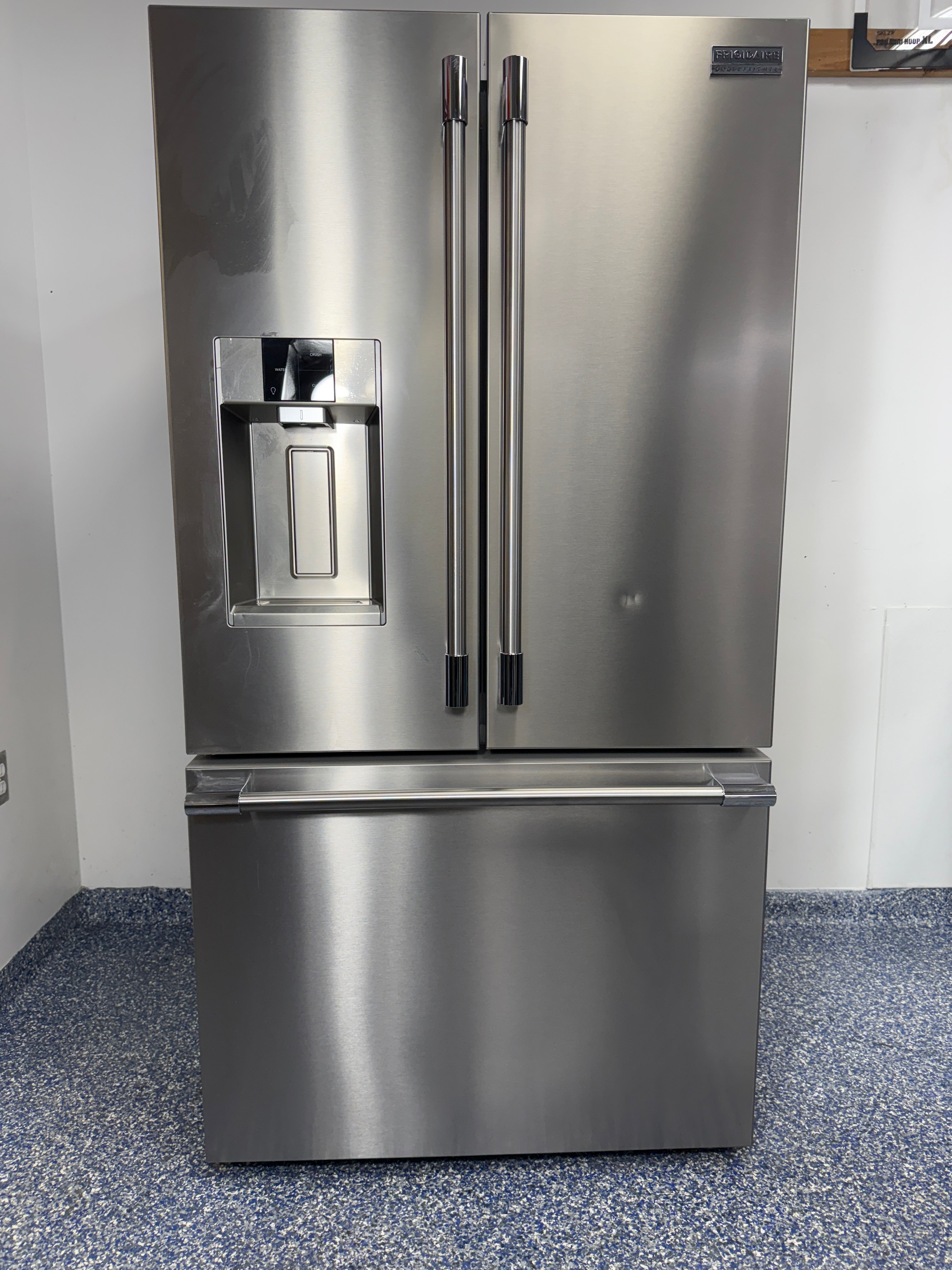 A full frontal image of the FRIGIDAIRE PRFS2883AF French door refrigerator, highlighting its Smudge-Proof® Stainless Steel finish and external dispenser. On sale at Appliance Shark - Scratch & Dent store | Kansas City.