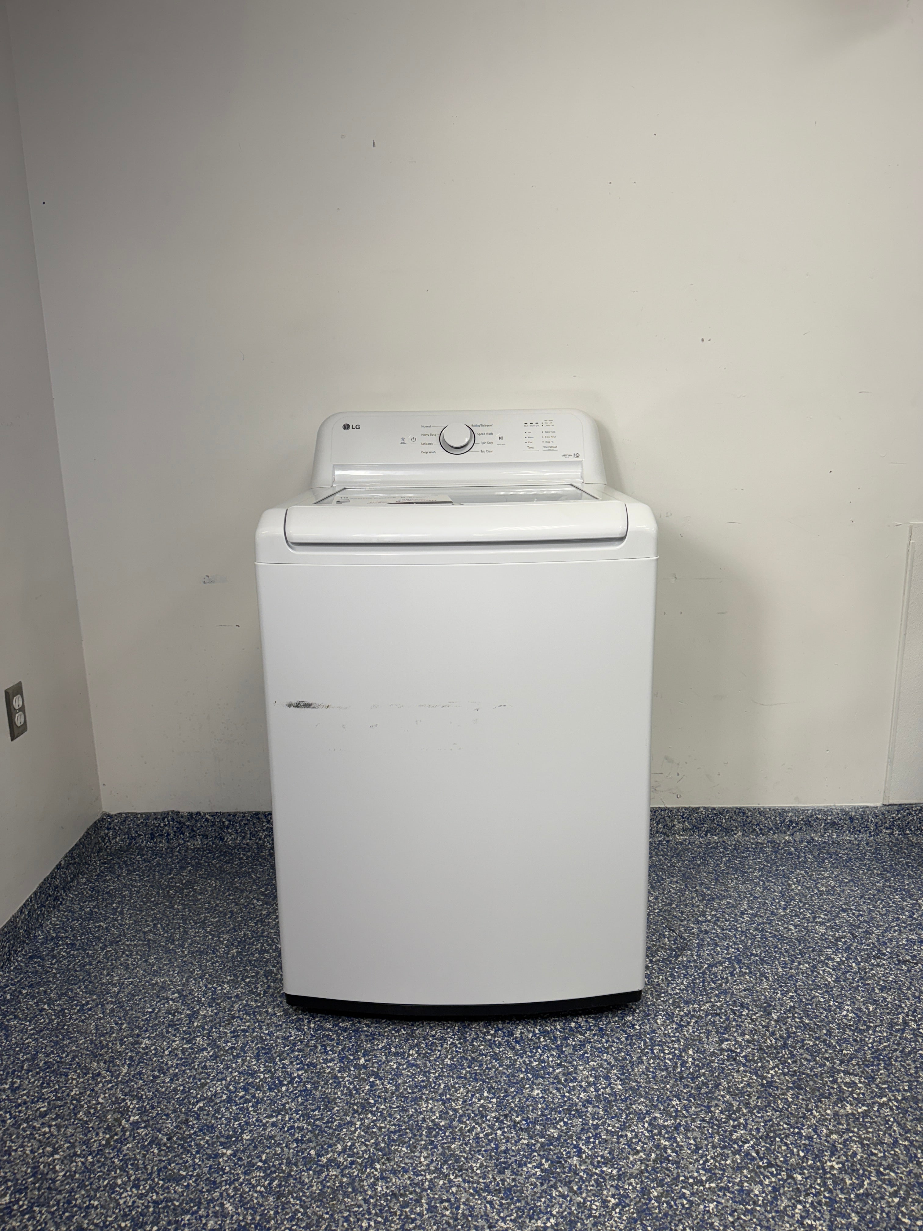 A full frontal image of the LG WT6105CW top-load washing machine, highlighting its classic white finish and knob controls. On sale at Appliance Shark - Scratch & Dent store | Kansas City.