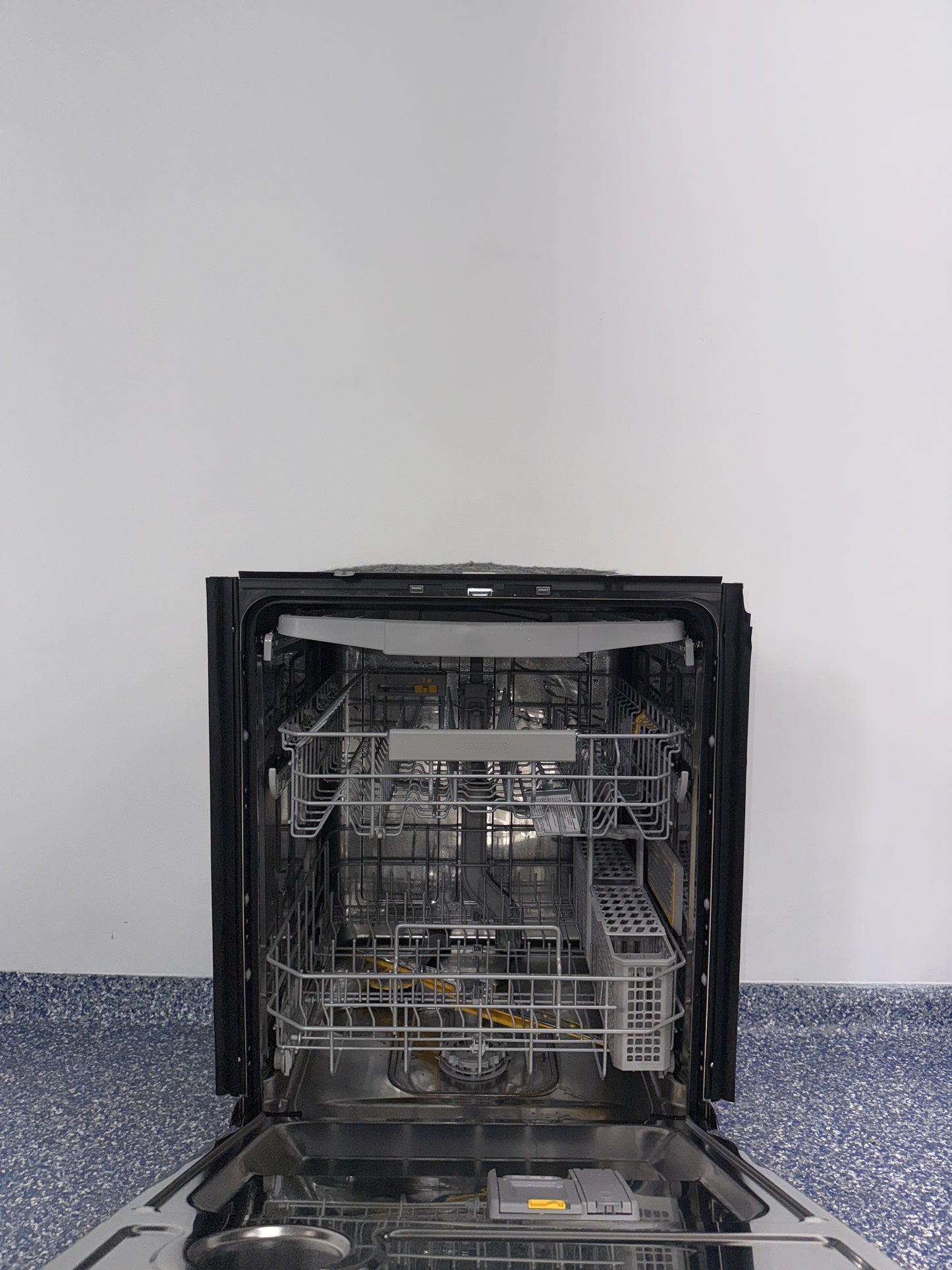 A view of the SAMSUNG DW80BB707012 dishwasher's interior, showing its convenient third rack for cutlery in an Overland Park home.