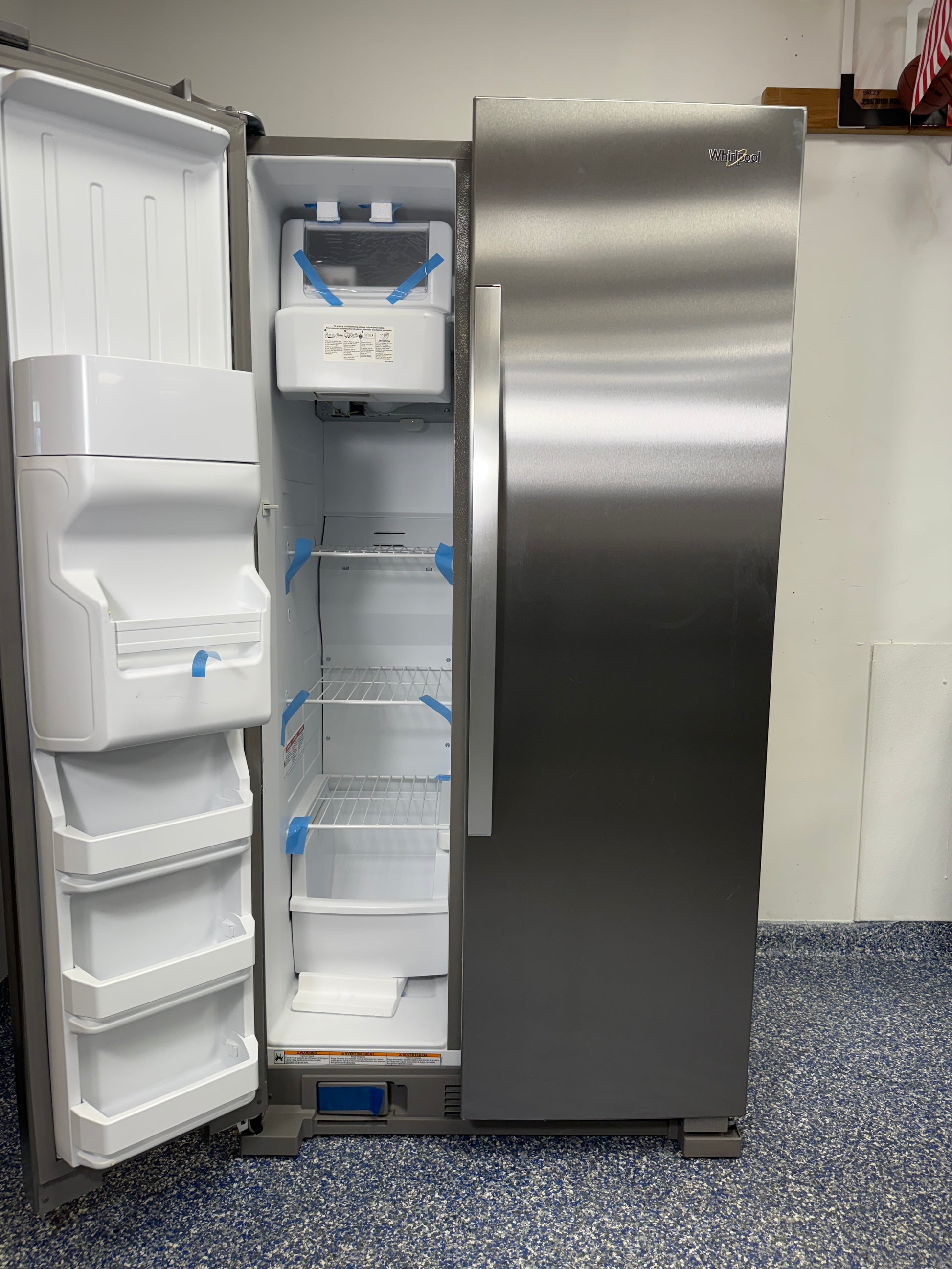 View of the interior of the Whirlpool WRS315SDHZ freezer, highlighting the indoor ice maker and wire shelving. On sale at Appliance Shark - Scratch & Dent store | Kansas City.
